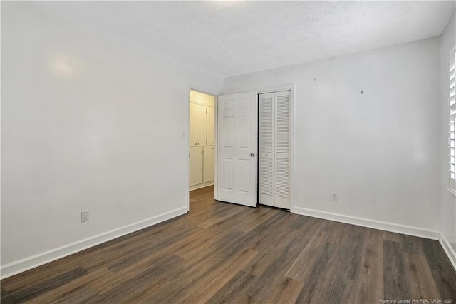 unfurnished bedroom with dark hardwood / wood-style floors and a closet