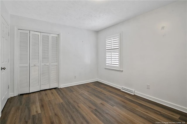 unfurnished bedroom featuring dark wood-type flooring, a closet, and a textured ceiling