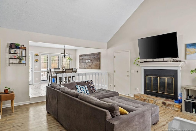 living room with lofted ceiling, a stone fireplace, and light wood-type flooring