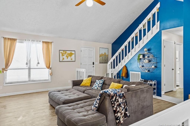 living room with lofted ceiling, hardwood / wood-style floors, a textured ceiling, and ceiling fan