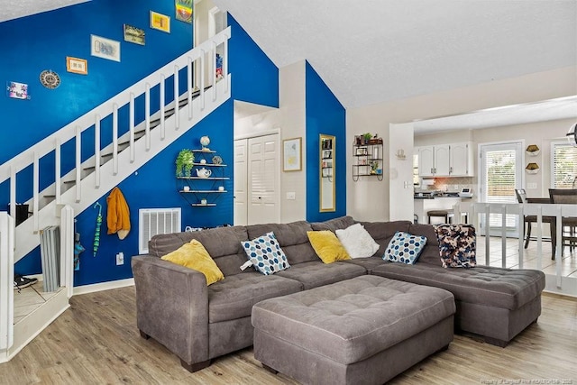 living room with high vaulted ceiling and light hardwood / wood-style floors