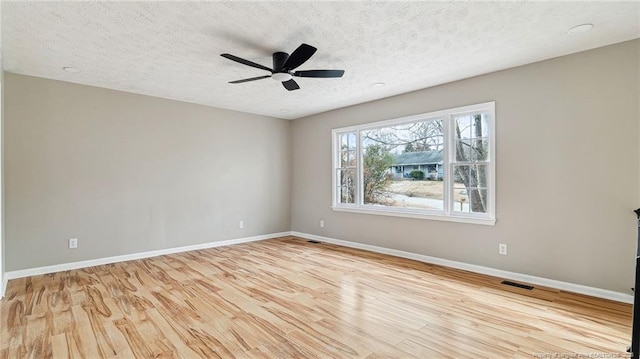 unfurnished room with ceiling fan, a textured ceiling, and light wood-type flooring