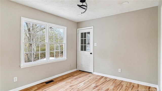 empty room featuring a textured ceiling and light hardwood / wood-style flooring