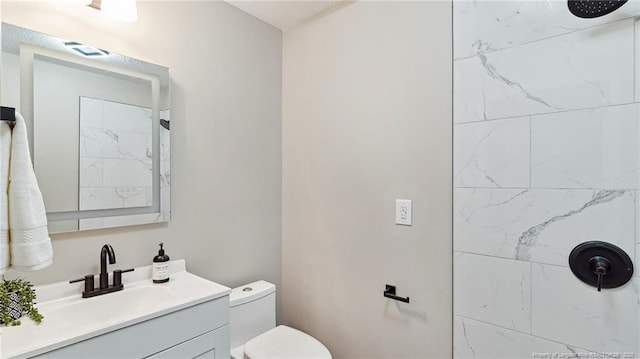 bathroom featuring vanity, toilet, and tiled shower