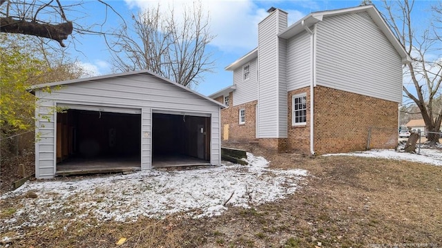 snow covered property featuring a garage and an outdoor structure