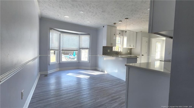 kitchen featuring white cabinets, decorative backsplash, hanging light fixtures, kitchen peninsula, and a textured ceiling