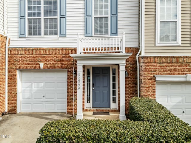 view of exterior entry featuring a garage and a balcony