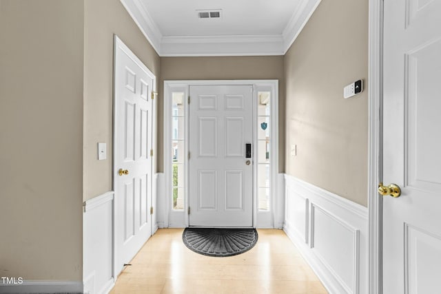 foyer with ornamental molding and light wood-type flooring