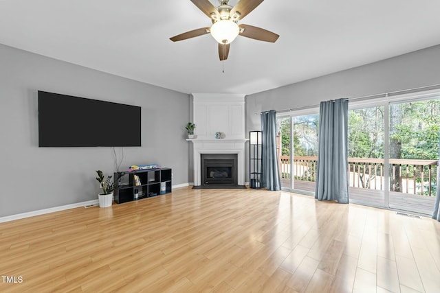 living room with ceiling fan, a large fireplace, and light wood-type flooring