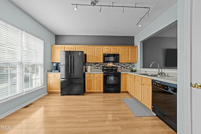 kitchen featuring light brown cabinetry, tasteful backsplash, sink, light hardwood / wood-style floors, and black appliances