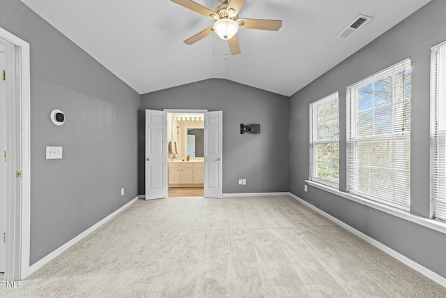 unfurnished bedroom featuring light carpet, vaulted ceiling, ceiling fan, and ensuite bathroom