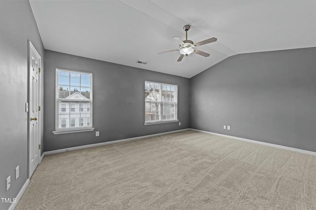 empty room featuring vaulted ceiling, light colored carpet, and ceiling fan