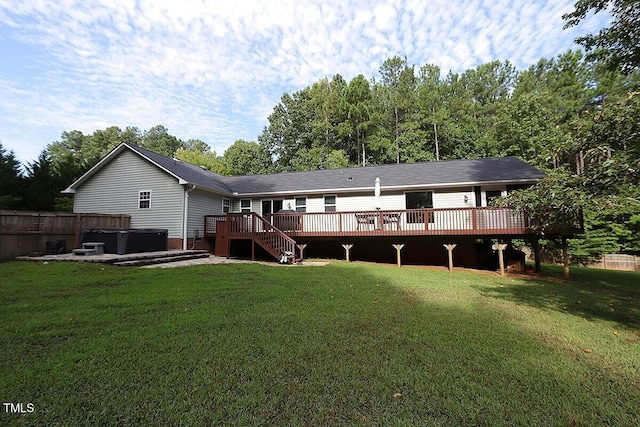 rear view of property with a wooden deck, a yard, and a hot tub