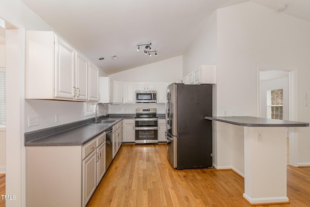 kitchen with white cabinetry, stainless steel appliances, a sink, and a kitchen breakfast bar