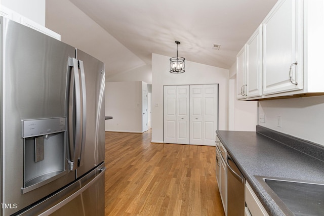 kitchen featuring light wood finished floors, dark countertops, hanging light fixtures, appliances with stainless steel finishes, and white cabinetry