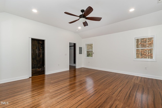 spare room featuring dark wood-style floors, vaulted ceiling, and baseboards