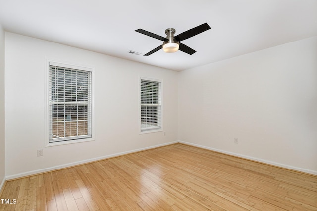 empty room with a ceiling fan, light wood-type flooring, visible vents, and baseboards