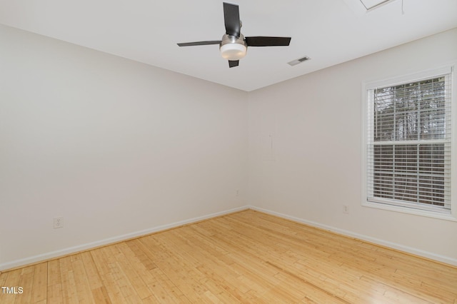 spare room featuring a ceiling fan, visible vents, baseboards, and wood finished floors