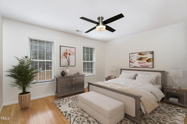 bedroom with a ceiling fan, baseboards, visible vents, and light wood finished floors