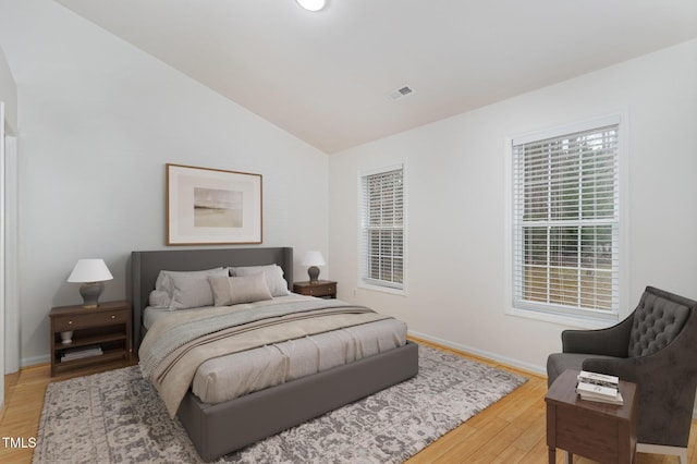 bedroom featuring vaulted ceiling, wood finished floors, visible vents, and baseboards