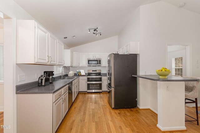 kitchen with stainless steel appliances, a breakfast bar, a peninsula, a sink, and white cabinets