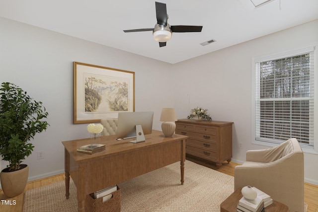 office with baseboards, light wood finished floors, visible vents, and a ceiling fan