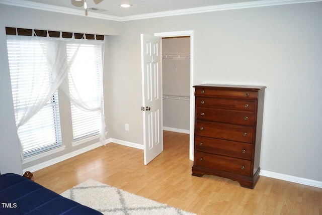 bedroom with multiple windows, a walk in closet, a closet, and light wood-type flooring