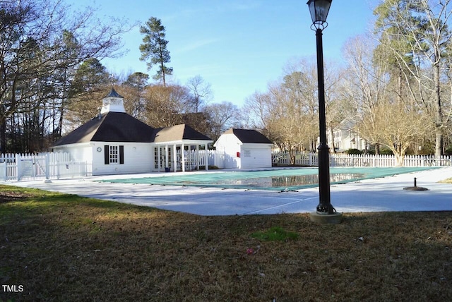 back of house featuring a patio, a covered pool, and a storage shed