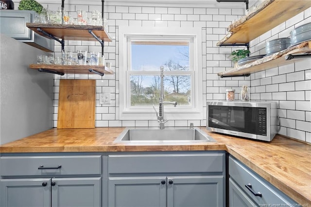 kitchen with butcher block counters, sink, and backsplash