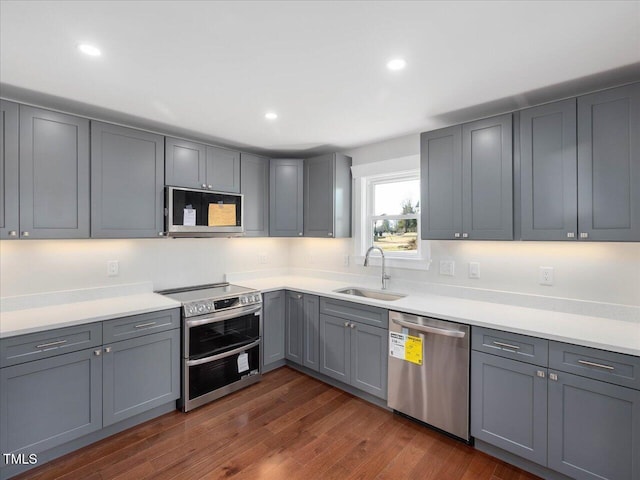 kitchen with dark wood-type flooring, stainless steel appliances, sink, and gray cabinetry