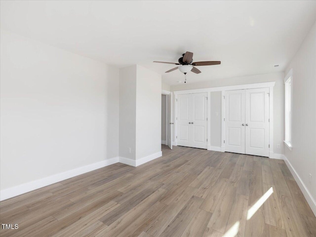 unfurnished bedroom with light wood-type flooring, two closets, and ceiling fan