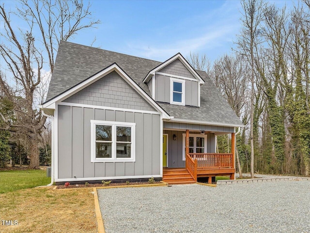 view of front of property featuring a front lawn, roof with shingles, a porch, and board and batten siding