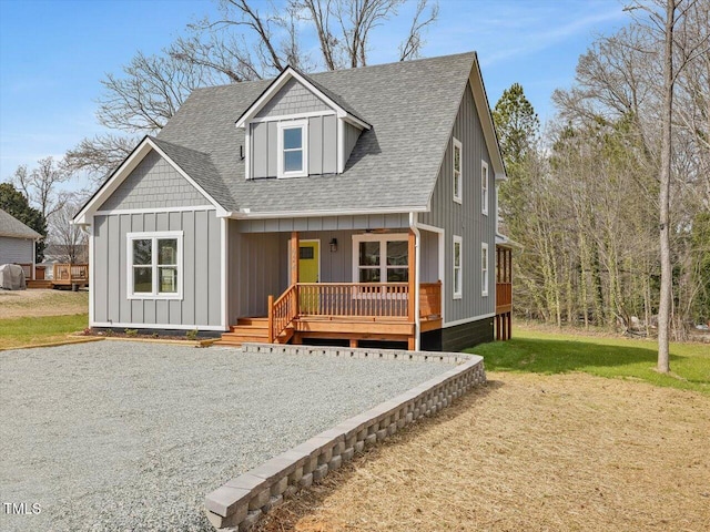 view of front of house featuring a front lawn, a porch, board and batten siding, and roof with shingles