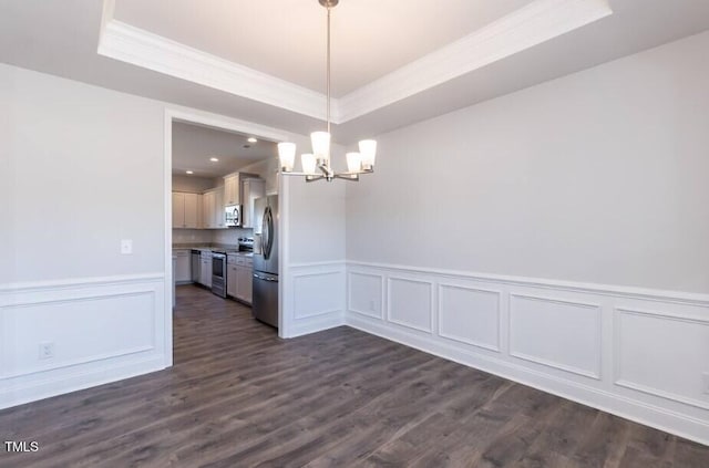 unfurnished dining area featuring dark hardwood / wood-style flooring, crown molding, an inviting chandelier, and a tray ceiling