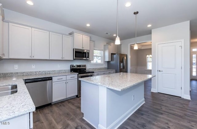 kitchen featuring pendant lighting, stainless steel appliances, light stone counters, and white cabinets