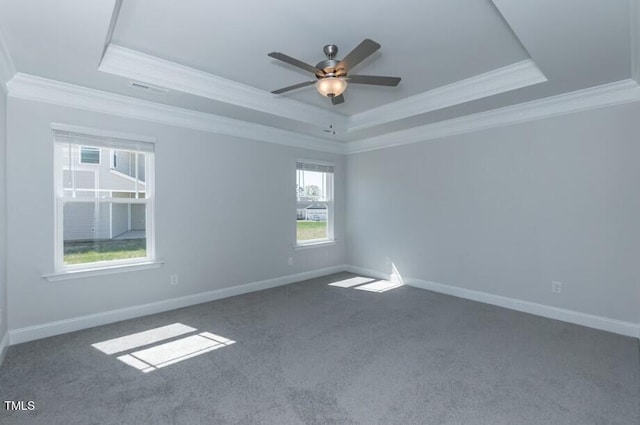 empty room with crown molding, a raised ceiling, and dark colored carpet