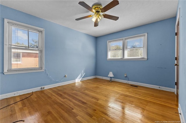 empty room with ceiling fan, a healthy amount of sunlight, and light hardwood / wood-style flooring