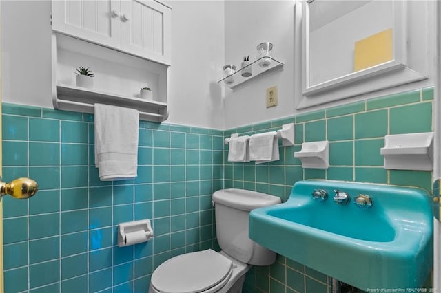 bathroom featuring sink, tile walls, and toilet