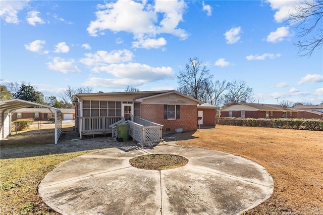 rear view of property with a carport, a sunroom, and a lawn