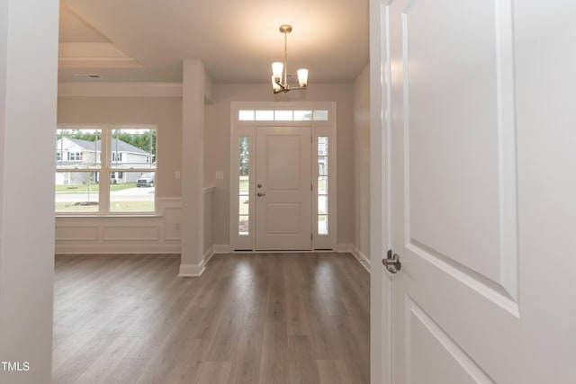 entrance foyer with crown molding, hardwood / wood-style floors, and a notable chandelier