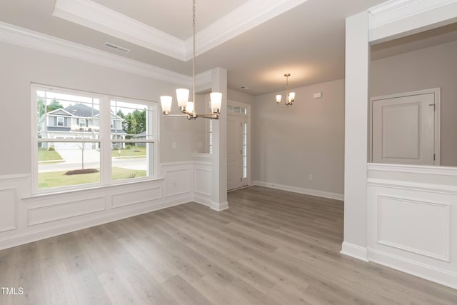 unfurnished dining area featuring crown molding, hardwood / wood-style floors, a notable chandelier, and a tray ceiling