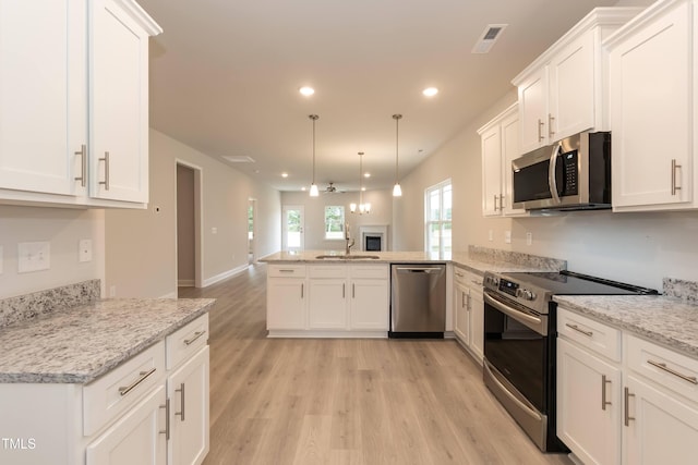 kitchen with pendant lighting, stainless steel appliances, kitchen peninsula, and white cabinets