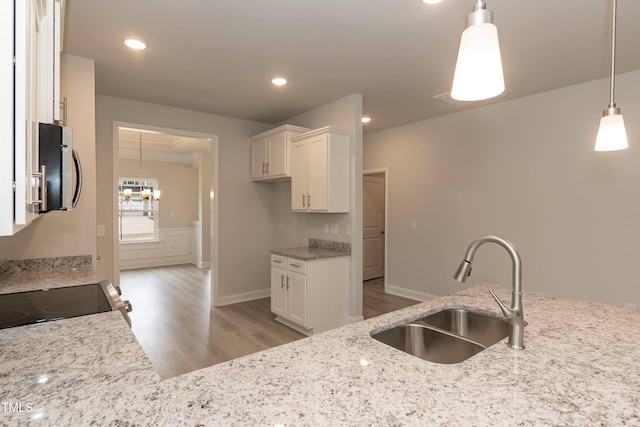 kitchen featuring sink, stove, light stone countertops, white cabinets, and decorative light fixtures