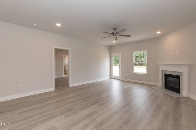 unfurnished living room with ceiling fan, light wood-type flooring, and a high end fireplace