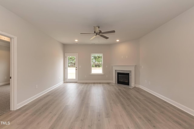 unfurnished living room with a high end fireplace, light hardwood / wood-style floors, and ceiling fan