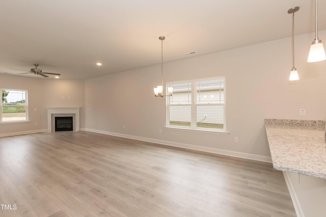 unfurnished living room with hardwood / wood-style floors and ceiling fan with notable chandelier