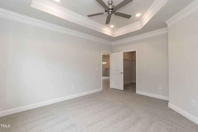 unfurnished bedroom with a walk in closet, ceiling fan, a raised ceiling, crown molding, and a closet