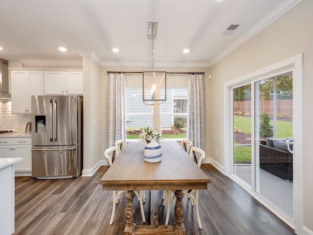 dining area with ornamental molding, dark wood-type flooring, and an inviting chandelier