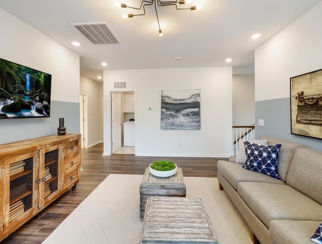 living room with an inviting chandelier, washer / clothes dryer, and hardwood / wood-style floors