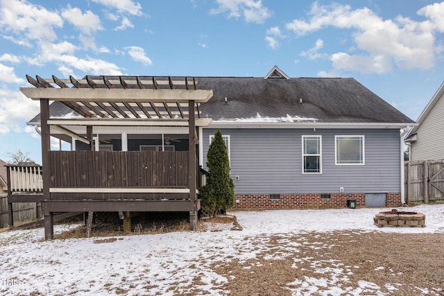 snow covered back of property with a pergola, a deck, and a fire pit